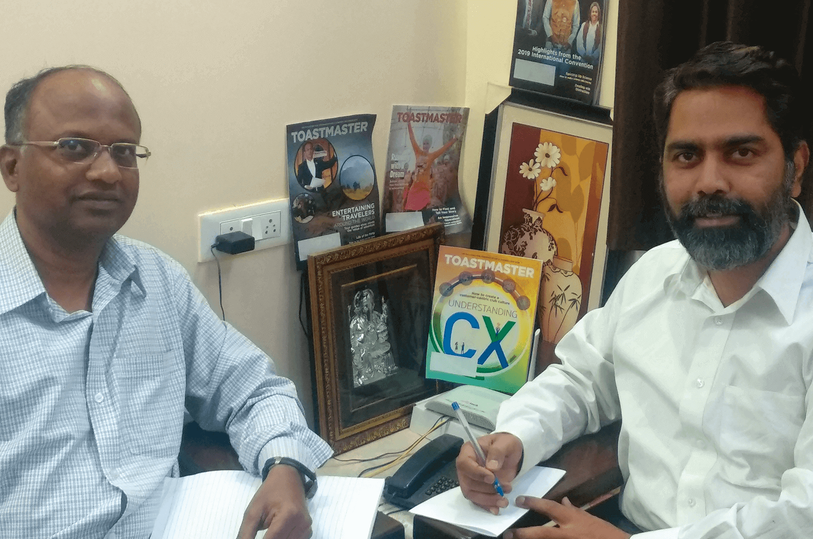 Two men in Toastmasters club posin with magazines