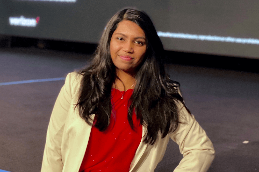 Woman in red shirt standing in front of stage and screen