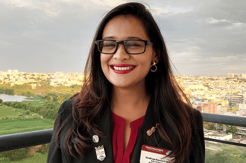 Woman posing outdoors in black jacket with pins